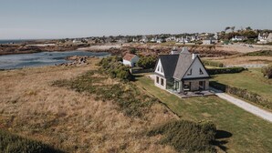 A coastal house with a large lawn, a patio, and a view of the sea. - Exceptional villa with ocean views—comfort and charm, Brittany (Lanildut)