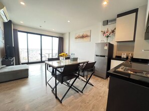 A modern kitchen with a dining area, a refrigerator, and a large window with a view. - Exclusive Sea View 2 Bed Room High Floor 2 Balcony (Pattaya)