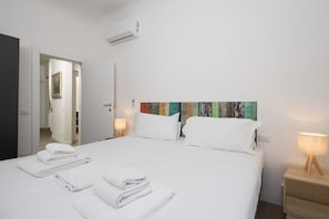 A hotel room with a bed, white towels, a colorful artwork on the wall, and a bedside lamp. - Serristori Riverside Apartment (Florence)