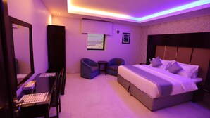 Una habitación de hotel moderna con una cama grande, un escritorio, dos sillas y un espejo amplio.