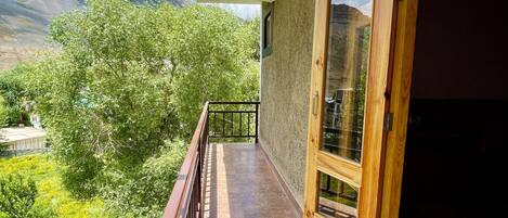 A balcony with a view of green trees and mountains.