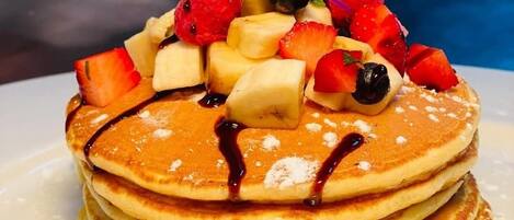 A stack of pancakes topped with fruit and syrup.