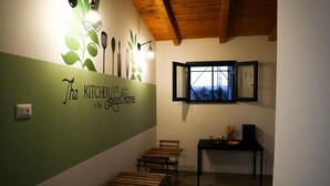 A kitchen area with a green wall, wooden benches, a window with a city view, and a table with kitchen utensils. - Ciuri's House (Catania)