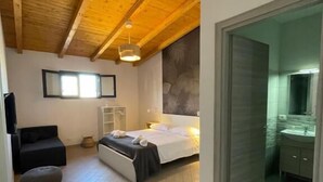 A bedroom with a bed, a sofa, a small table, and a window. - Ciuri's House (Catania)