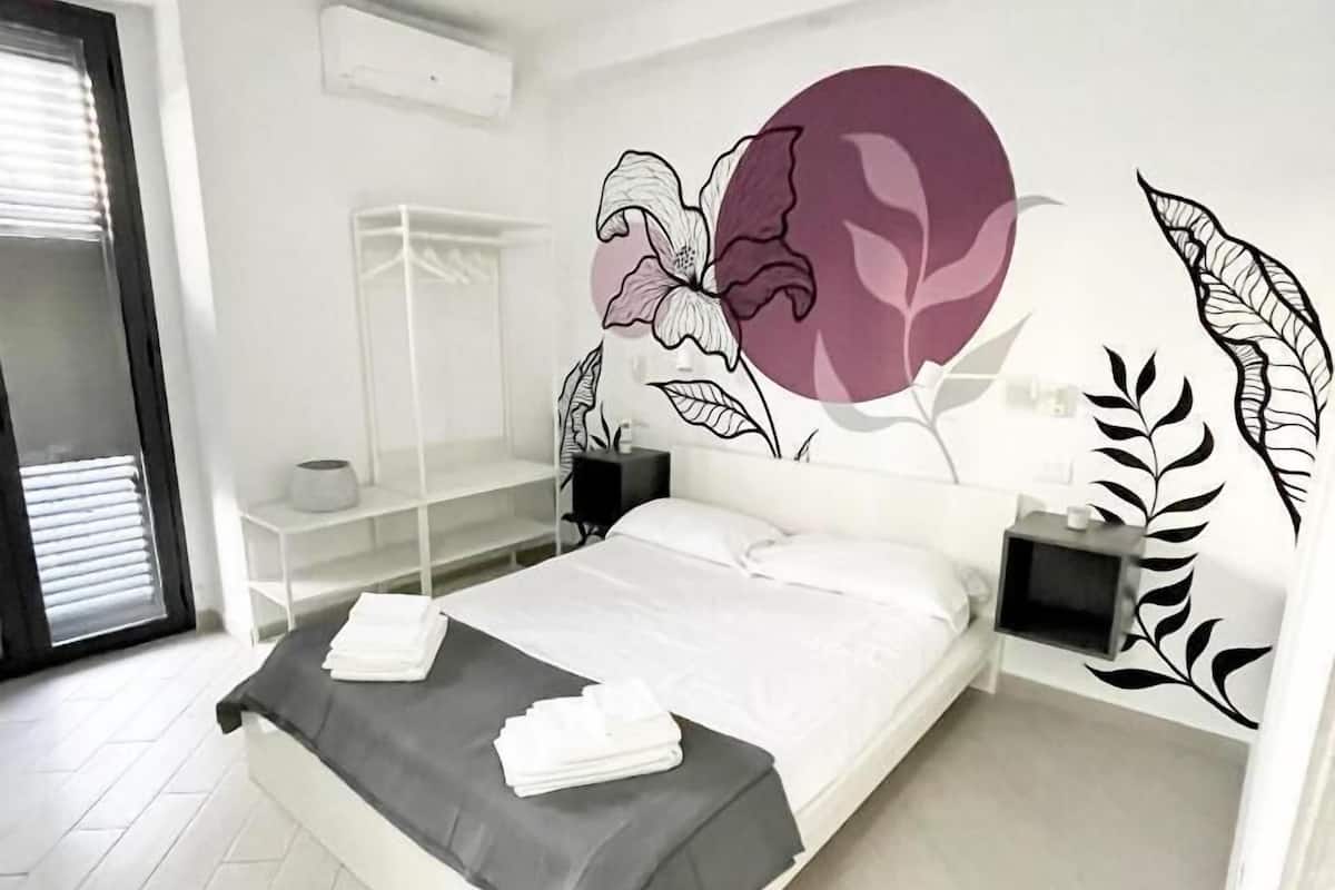 A modern bedroom with a bed, bedside tables, a wardrobe, and a large wall mural.