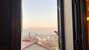 A window with a view of a cityscape, including buildings and a dome structure. - Ciuri's House (Catania)