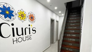 A hallway with a staircase and a wall with the text 'Ciuris HOUSE' and decorative flowers. - Ciuri's House (Catania)