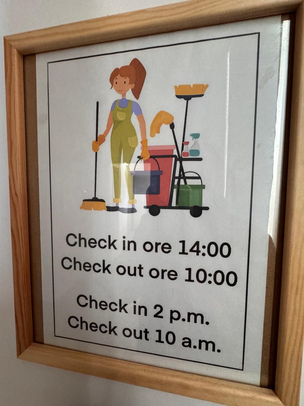 A framed sign with a cleaning lady illustration and check-in/out times.