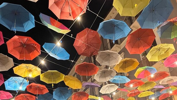 A crowded indoor space with numerous colorful umbrellas suspended from the ceiling. - Ciuri's House (Catania)