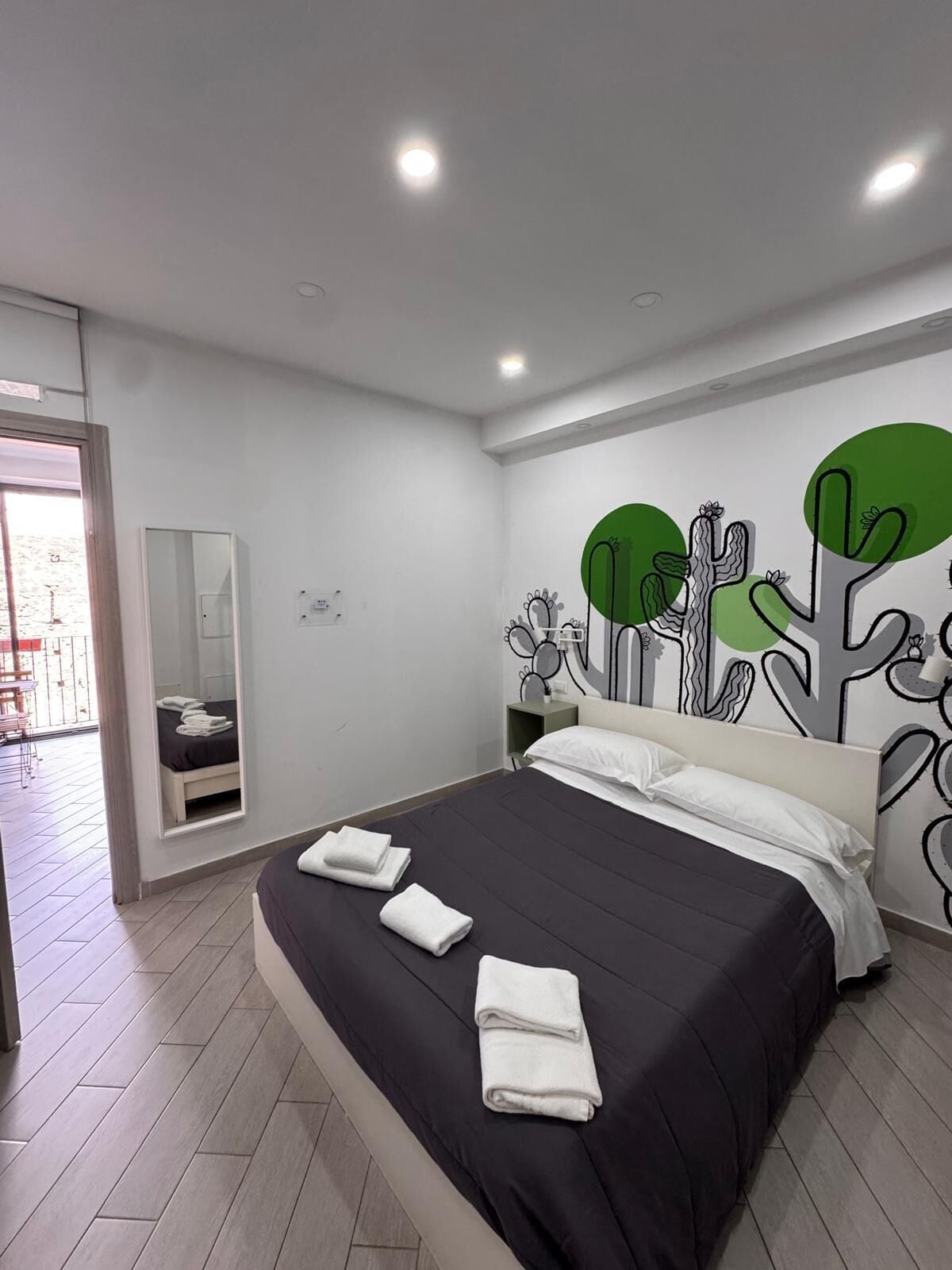 A modern hotel room with a bed, a mirror, and a wall with abstract art.