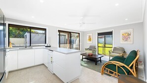 A compact kitchen with a dining area, a ceiling fan, and a view of the backyard through a sliding door. - 12 Borang @ The Point (Potato Point)