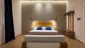 Une chambre d’hôtel moderne avec un grand lit, des tables de chevet, un banc en bois et une armoire.