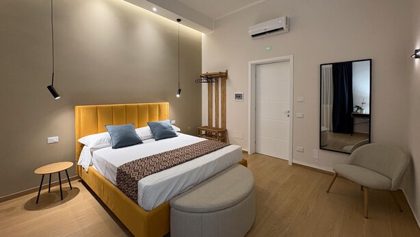 Une chambre à coucher moderne avec un lit, une table de chevet, une chaise et un miroir.