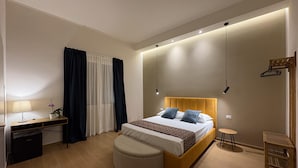 Une chambre à coucher moderne avec un lit, une table de chevet, une lampe et un petit tabouret.