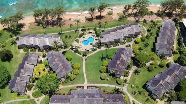 Vista aérea de un resort con varias edificaciones, una piscina central y una playa.