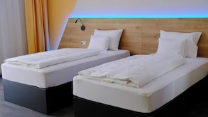 Dos camas individuales con cabeceros de madera y una luz nocturna.