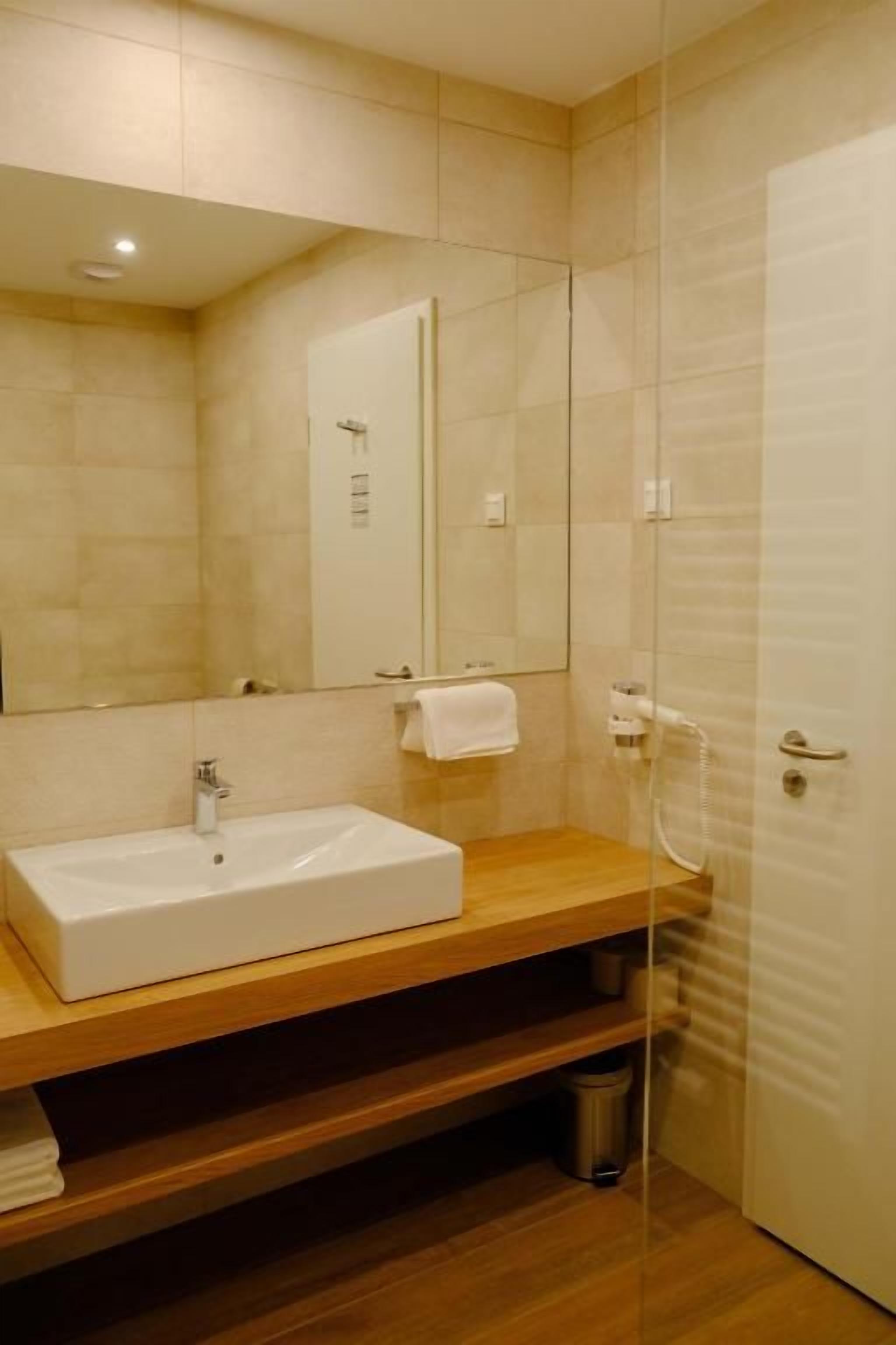 Un baño moderno con un lavamanos rectangular, un espejo y una cabina de ducha de vidrio.