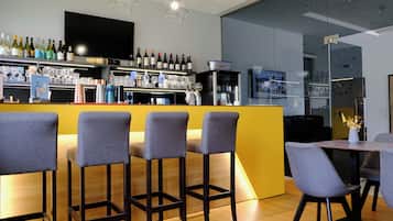 Eine Bar mit Hockern, einer Theke mit Flaschen, Gläsern und einem Fernseher.