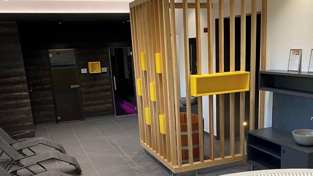 Un espacio de spa con un jacuzzi, separaciones de madera y sillones de descanso.