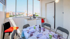 Un petit coin repas avec une table dressée pour quatre personnes, une fenêtre donnant sur la ville et une kitchenette.