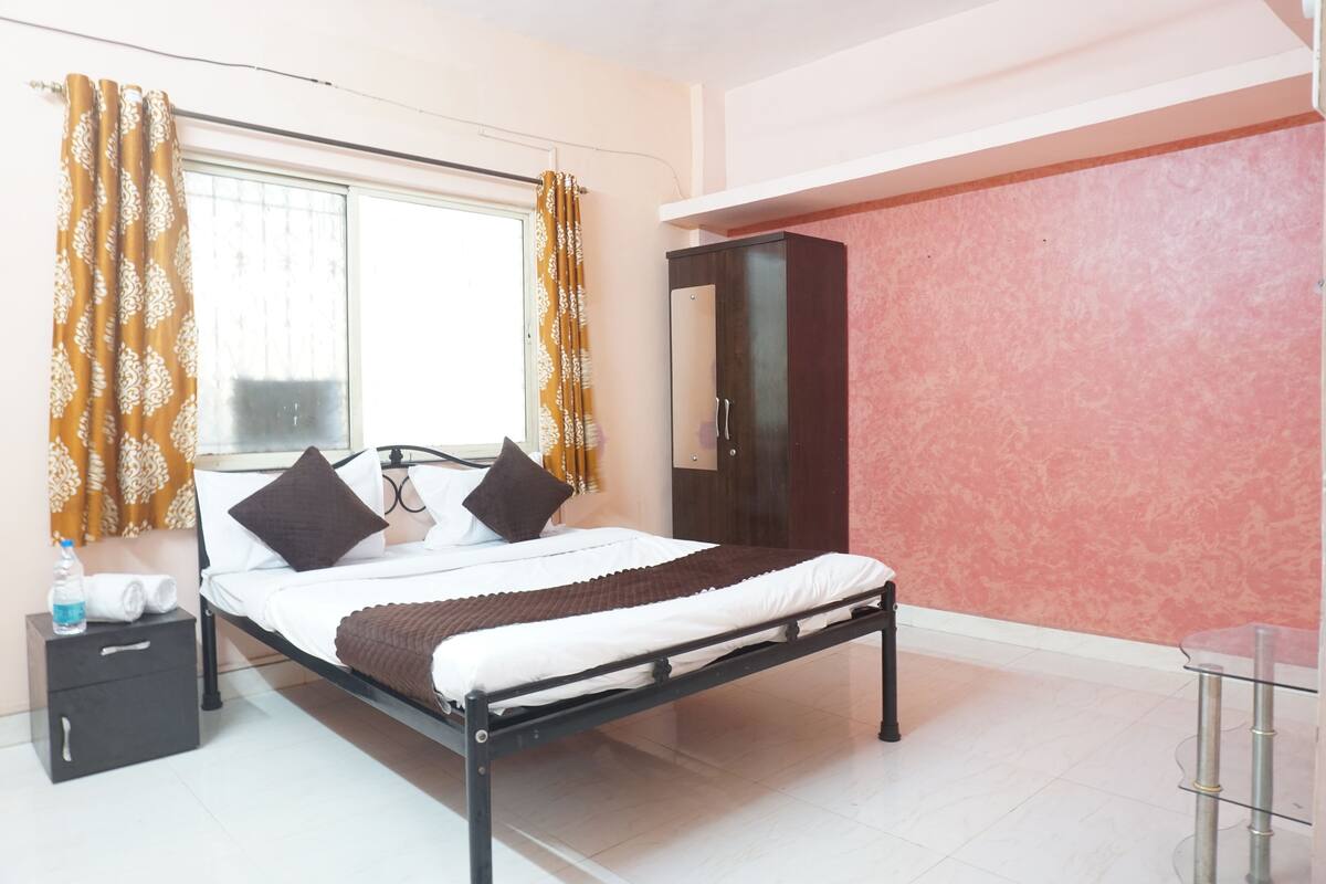 Une chambre bien rangée, avec un lit, une armoire, une table de chevet et une fenêtre avec des rideaux.