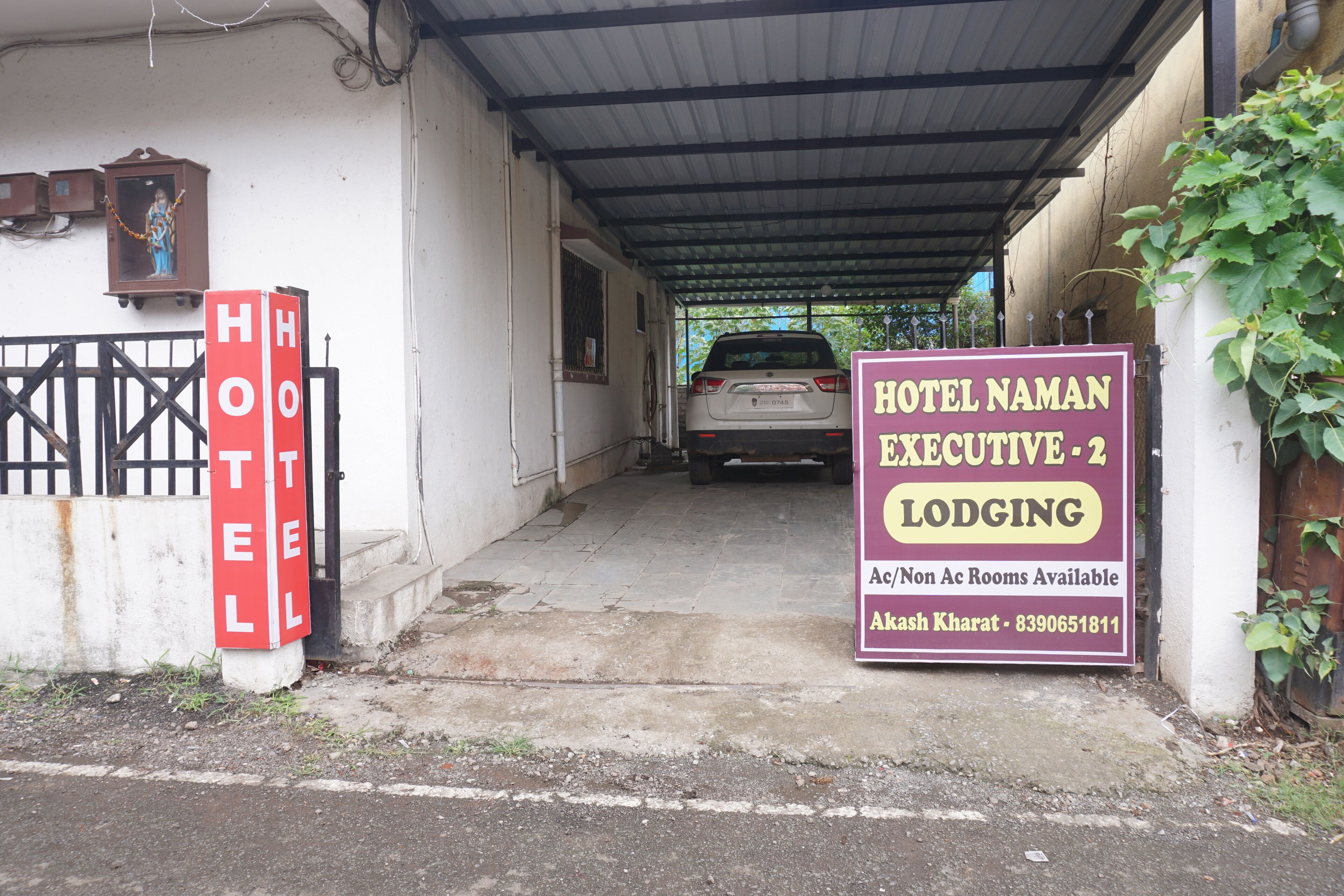 Hoteleingang mit einem parkenden Auto und einem Schild für Hotel Naman Executive 2 Unterkunft.