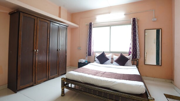 Un dormitorio con cama, armario y ventana con cortinas.