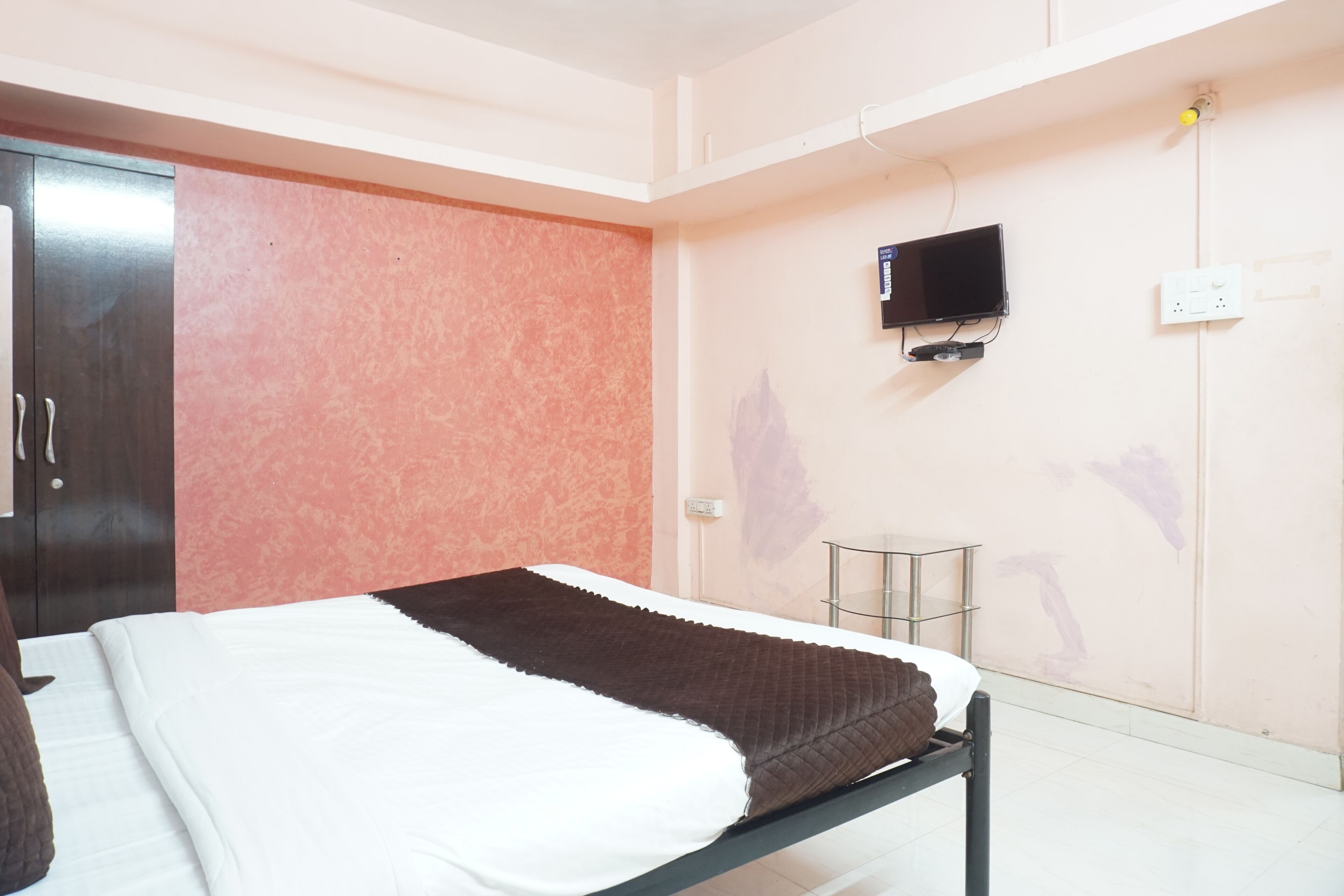 A bedroom with a bed, a television mounted on the wall, and a wardrobe.