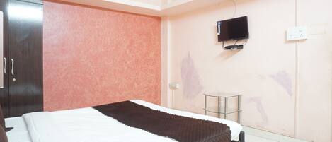 A bedroom with a bed, a television mounted on the wall, and a wardrobe.