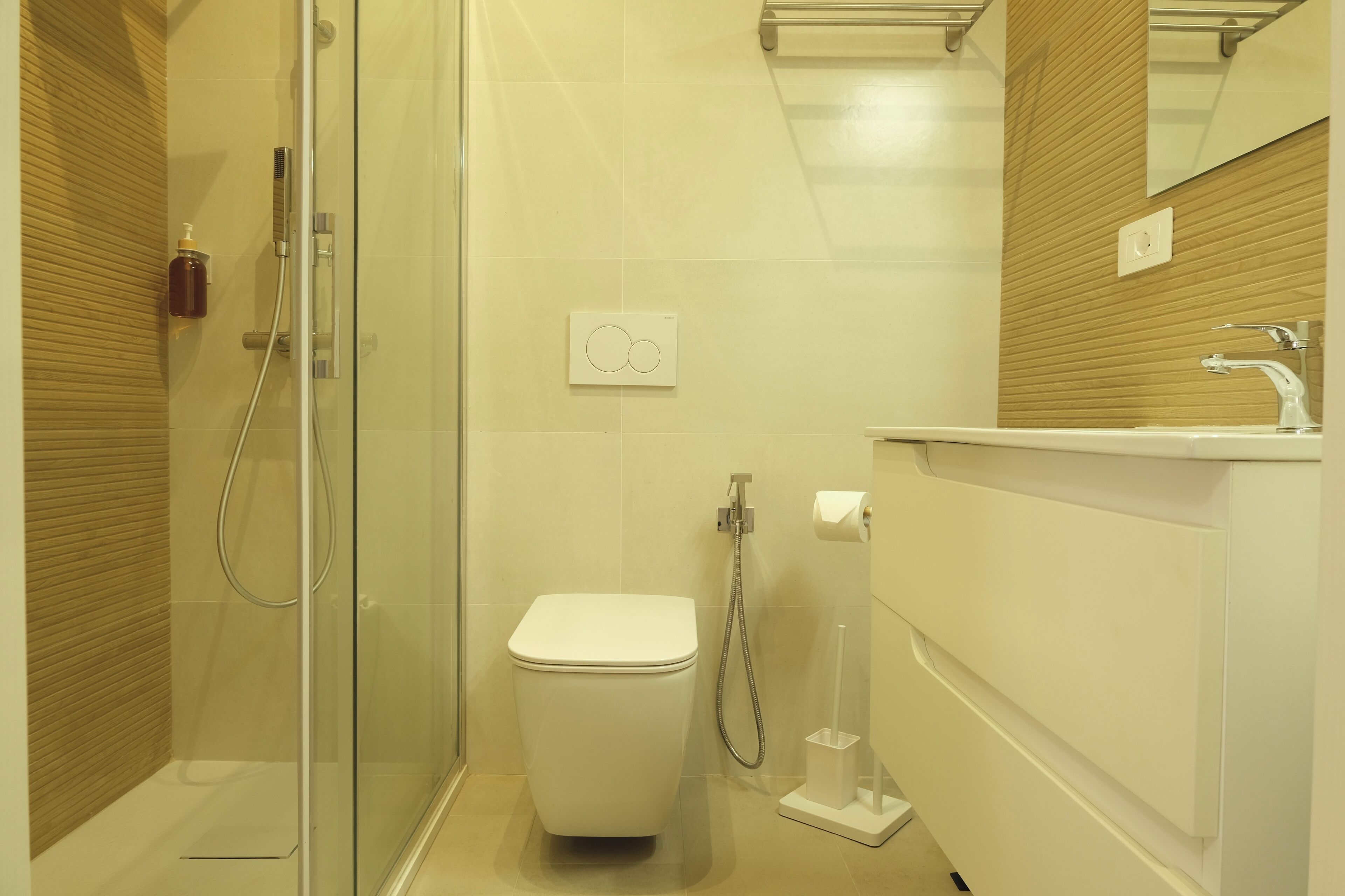 Une salle de bain moderne avec une douche à parois de verre, des toilettes blanches et un meuble-lavabo avec un miroir.