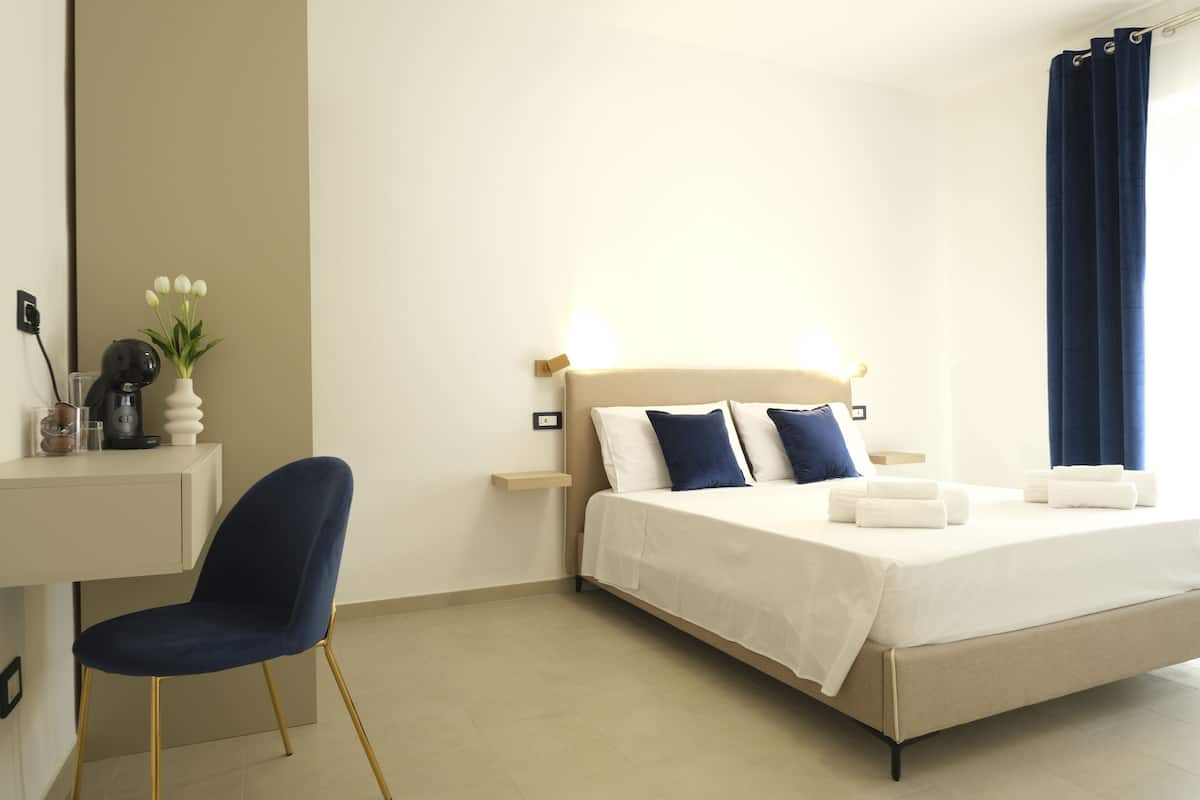 A hotel room with a bed, bedside tables, a desk, and a chair.