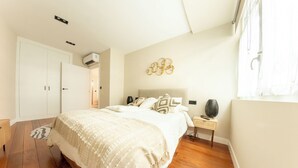 Een slaapkamer met een bed, nachtkastje en een wandairconditioner.