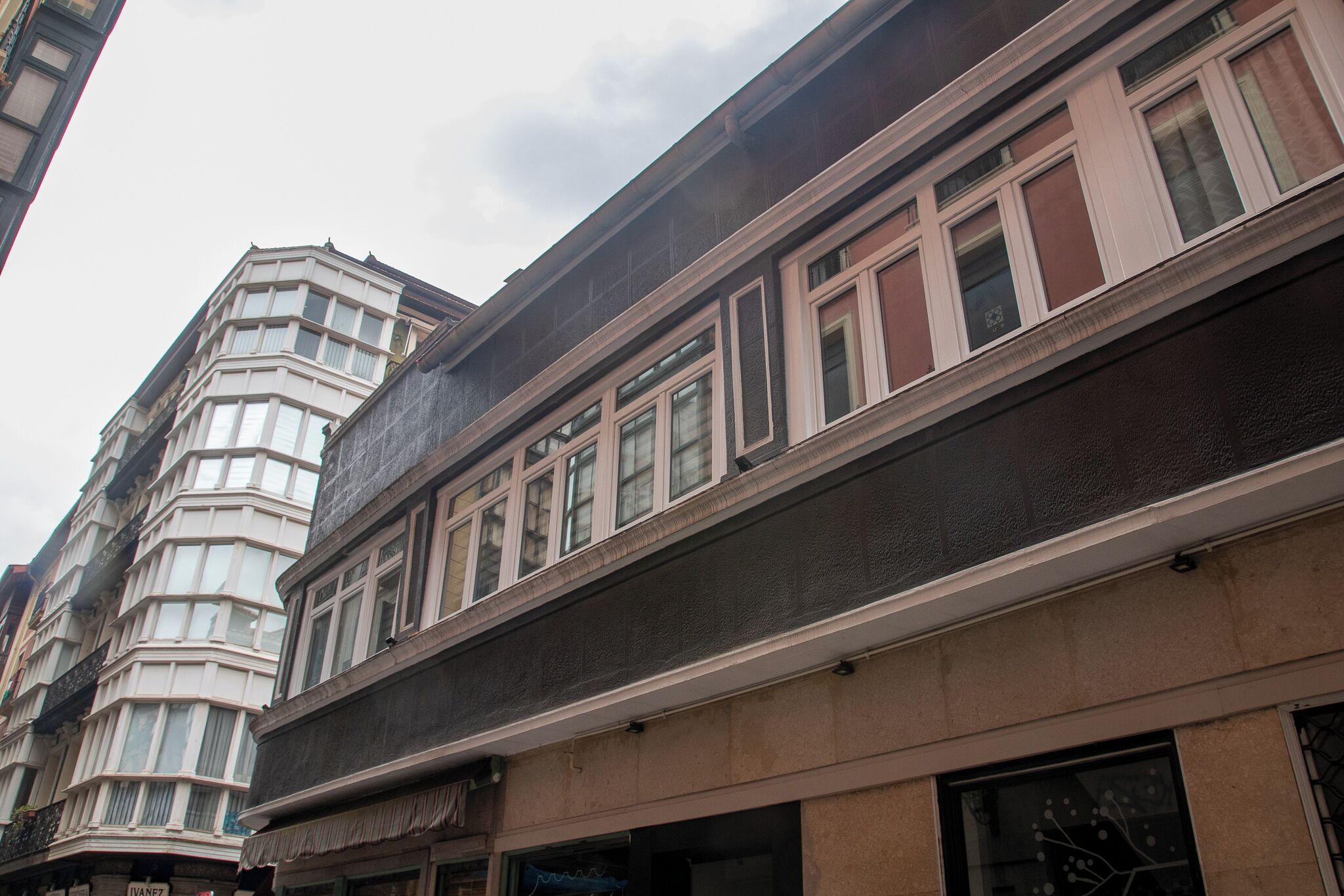 A multi-story building with a corner bay window and a flat facade.