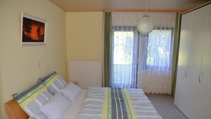 Une chambre à coucher avec un lit, une fenêtre avec des rideaux, un radiateur et un tableau accroché au mur.