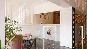 A reception area with a marble counter, framed pictures on the wall, and a potted plant. - Hotel Lakefront (Ranchi)