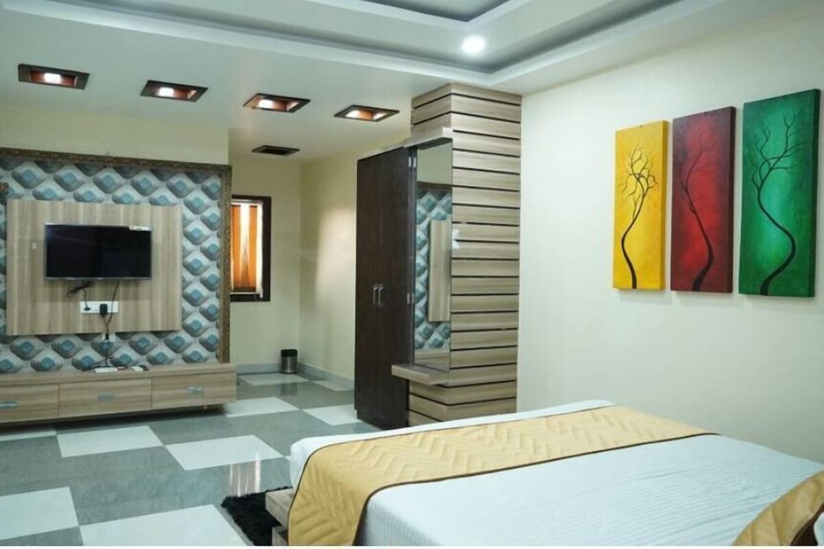 Un dormitorio moderno con un televisor montado en la pared, un armario y tres cuadros abstractos.