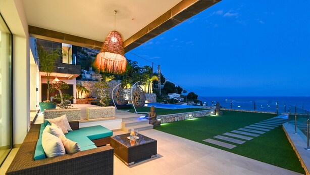 A modern outdoor lounge area with a sofa, coffee table, and decorative lighting. - Villa Bali by Marhen Homes (Javea / Xàbia)