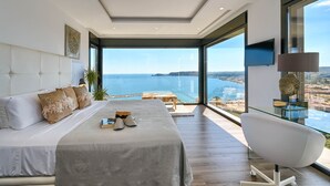 A modern bedroom with a large bed, a view of the sea, and a glass table. - Villa Bali by Marhen Homes (Javea / Xàbia)