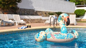 Ein Schwimmbecken mit Schwimm-Schwanen, Liegestühlen und einer Steinmauer.