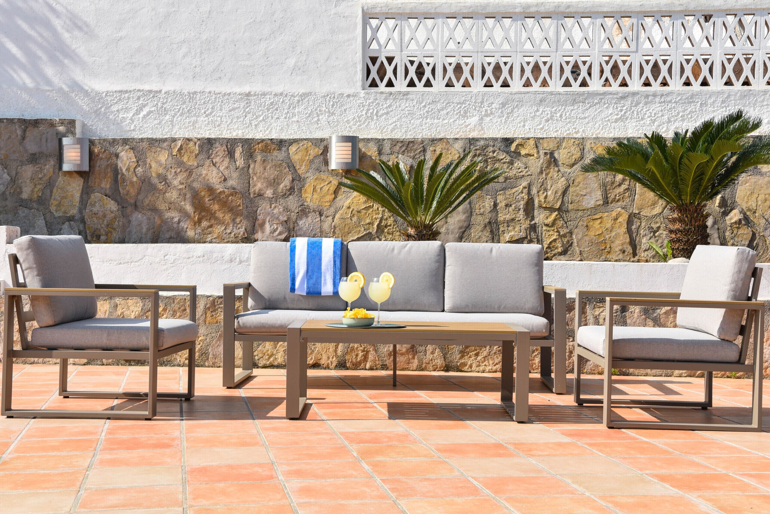 Un espacio al aire libre con muro de piedra, dos sofás y dos sillones.