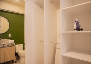 A bathroom with a toilet, a sink with a marble countertop, a mirror, and a shelf with an iron. - w*| Elegant 2BR w/ Great Balcony in Miraflores (Miraflores)