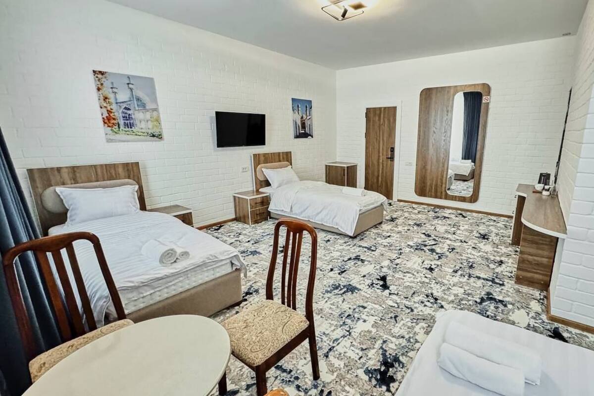 A hotel room with two beds, a TV, a mirror, and a small desk.