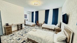 A hotel room with two beds, a small desk, a chair, and a TV mounted on the wall. - Siab Boutique Hotel (Samarkand)