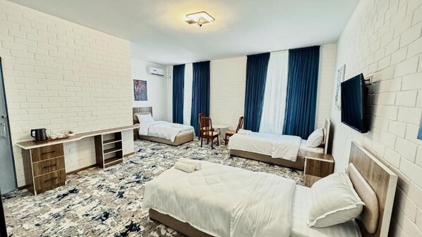 A hotel room with two beds, a small desk, a chair, and a TV mounted on the wall.