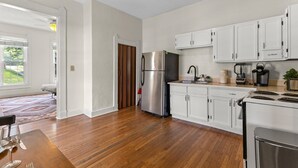 A modern kitchen with white cabinets, stainless steel appliances, and a wooden floor. - Simple Comfort  1 Bed 1 Bath Near Downtown Indy (Indianapolis)