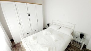 Une chambre à coucher avec un lit, une armoire blanche et des tables de chevet.