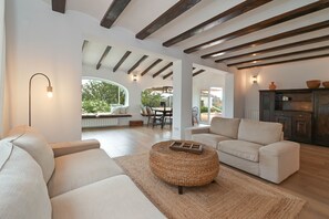 Un vaste salon doté d’un haut plafond, d’une cheminée et d’un coin repas visible à travers une arche ouverte.