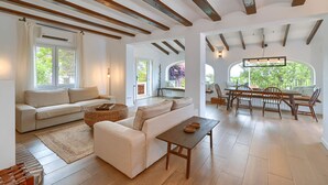 Ein geräumiges Wohnzimmer mit einer Couch, einem Couchtisch und einem Essbereich mit Stühlen und einem Tisch.