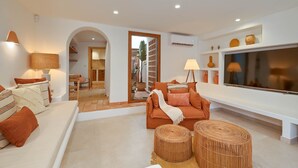 A modern living room with a sofa, ottomans, and a TV. - Casa Paraiso by Marhen Homes (Javea / Xàbia)