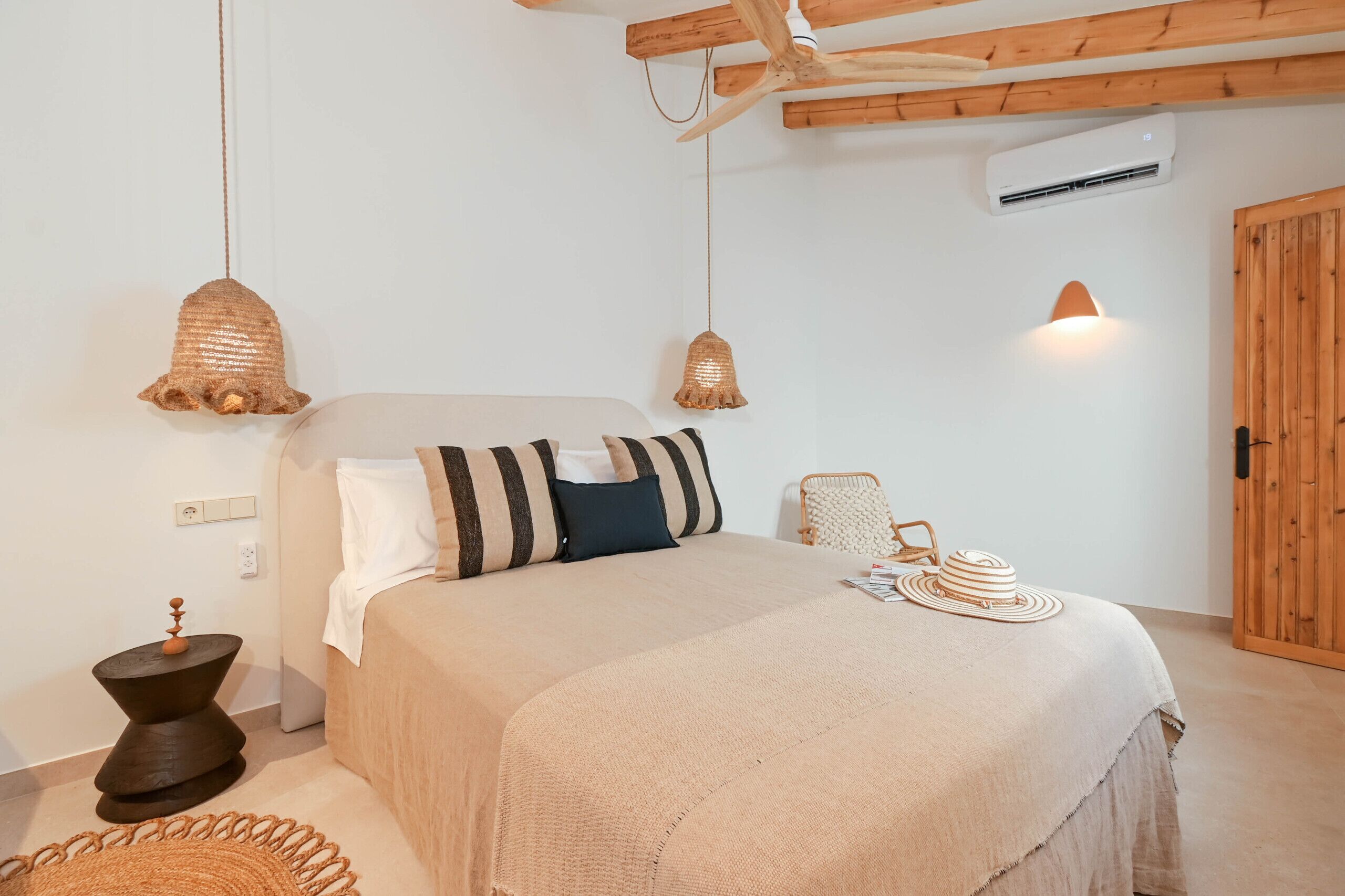 A bedroom with a bed, bedside table, lamp, and a wooden door.